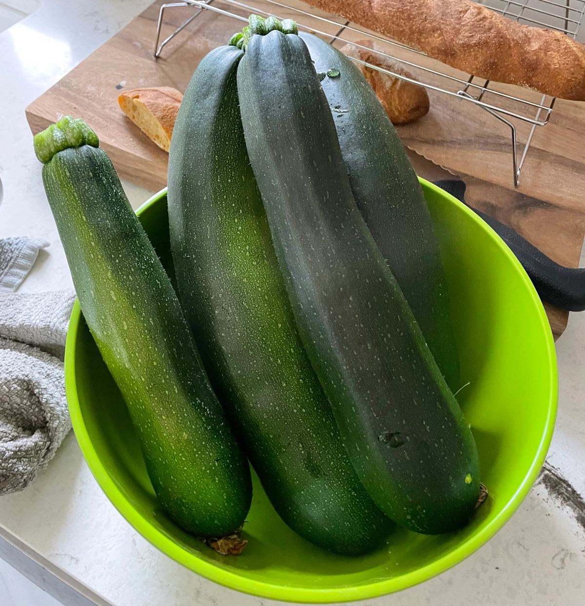 Zucchini in a green bowl on a kitchen counter